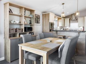 a kitchen and dining room with a wooden table and chairs at Turnberry Lodge in Girvan