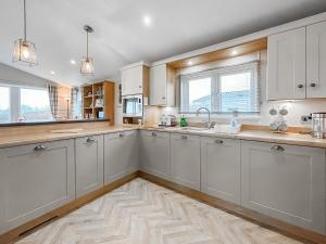 a kitchen with white cabinets and a wooden floor at Turnberry Lodge in Girvan +7 photos