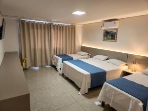 a hotel room with two beds and a window at Itumbiara Palace Hotel in Itumbiara