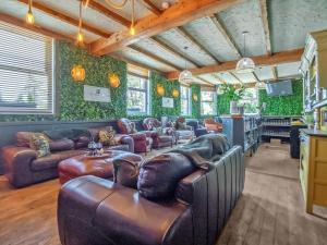 a living room with leather furniture and green walls at Alderfalls - Exclusive Private Pub Experience in Coelbren