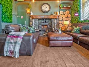 a living room with leather furniture and a fireplace at Alderfalls - Exclusive Private Pub Experience in Coelbren