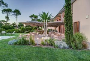 an outdoor patio with tables and an umbrella at Arli Hotel Hideaway Punta Ala - Adults Only in Punta Ala