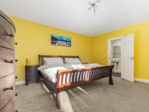 a bedroom with a bed and a yellow wall at The Garden Apartment in Peel