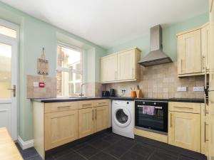 a kitchen with wooden cabinets and a washing machine at The Garden Apartment in Peel