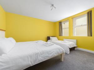 two beds in a room with yellow walls at The Garden Apartment in Peel +3 photos