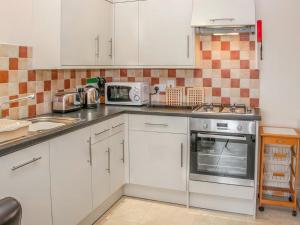 a kitchen with white cabinets and a stove top oven at Cut Lloi in Llanfair Caereinion