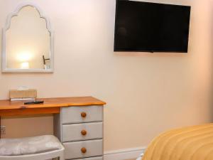 a bedroom with a dresser and a television on the wall at Cut Lloi in Llanfair Caereinion +3 photos