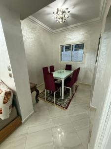 a dining room with a table and red chairs at Pavillon corniche Bord de mer Proche Centre in Mohammedia