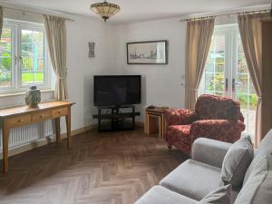 a living room with a tv and a couch and a chair at The Cottage in Castle Hedingham
