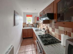 a small kitchen with a stove and a sink at The Cottage in Castle Hedingham