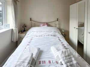 a bedroom with a white bed with towels on it at The Cottage in Castle Hedingham +3 photos