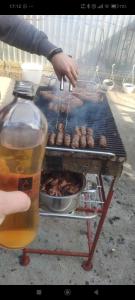a person cooking meat on a grill with a drink at DOR de CIMIȘLIA in Cimişlia