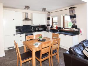 a kitchen and dining room with a wooden table and chairs at One Eden Cottage - Ukc6253 in Linlithgow