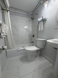a white bathroom with a toilet and a sink at Casablanca Oceanside Inn in Ocean City +25 photos