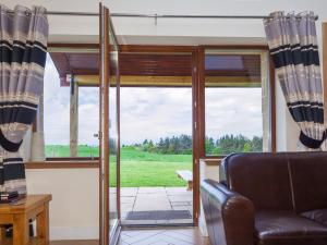a living room with a couch and a sliding glass door at One Eden Cottage - Ukc6253 in Linlithgow