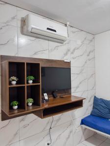 a room with a desk with a tv and a wall at Casa Sossego Com Piscina Aquecida, Hidro e Cascata in Peruíbe