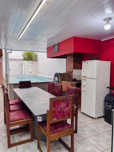 a kitchen with a table and chairs and a refrigerator at Casa Sossego Com Piscina Aquecida, Hidro e Cascata in Peruíbe