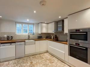 a large kitchen with white cabinets and appliances at Hailey Cottage in Chipping Norton