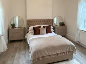 a bedroom with a large bed with two mirrors at Joss Bay Days in Broadstairs