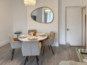 a dining room table with chairs and a mirror at Joss Bay Days in Broadstairs