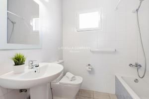 a white bathroom with a sink and a toilet at Villa FLEUR in Cala en Porter