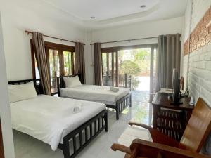 a bedroom with two beds and a tv and a balcony at Samnaree Garden House in Ban Phae Mai