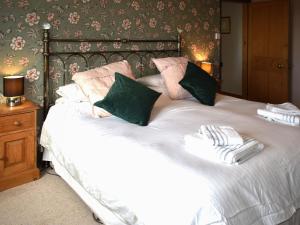 a large white bed with green and pink pillows at Little Gubbs in West Buckland