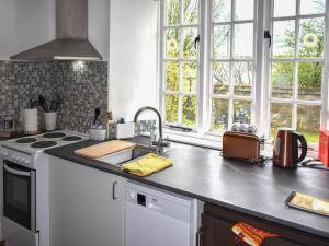 a kitchen with a sink and a stove and windows at Little Gubbs in West Buckland +4 photos
