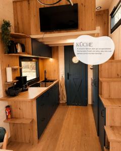 Eine Küche mit schwarzen Schränken und einem Fernseher an der Wand. in der Unterkunft Tinyhouse WeserNest in Sandstedt