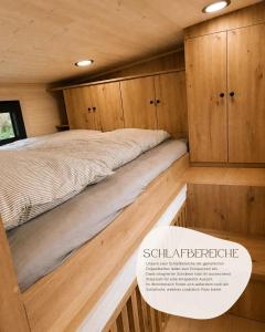 ein Bett in einem Zimmer mit Holzschränken in der Unterkunft Tinyhouse WeserNest in Sandstedt