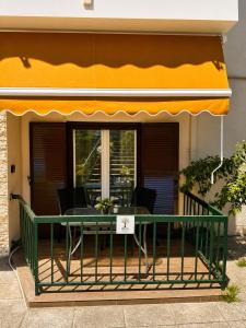 a patio with a green table and a yellow awning at Olive tree Apartment Kanoni in Kanoni