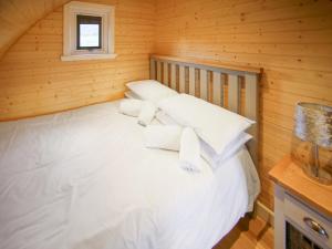 a bed in a wooden room with white pillows at Dougie's Pod in Acharacle