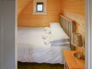 a bed in a wooden cabin with white sheets and pillows at Dougie's Pod in Acharacle