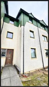 a large white building with a brown door at Super-King Room Tobermory with shared bathroom in Tobermory