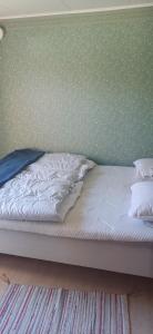 an unmade bed in a bedroom with a green wall at Black Pearl in Höjaholm