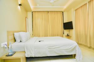 a hotel room with a white bed and a table at Hotel Shri Ram Residency in Belgaum