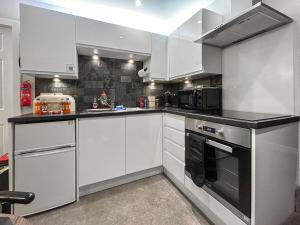 a kitchen with white cabinets and a black counter top at The Lade in Kilsyth