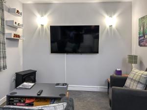 a living room with a table and a tv on a wall at The Lade in Kilsyth