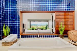 a blue tiled bathroom with a tub and a mirror at Luang Prabang View Hotel in Luang Prabang
