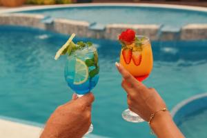 two people holding up two cocktails in front of a pool at Pousada Jagatá in Tutóia