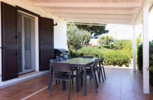 a patio with a table and chairs on a porch at Villa Selas in Leporano Marina