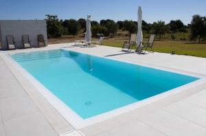 a large swimming pool with chairs at Villa Selas in Leporano Marina