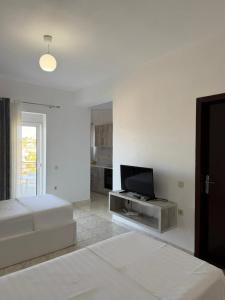 a white room with a bed and a flat screen tv at Villa Mirjan in Sarandë
