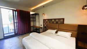 a bedroom with a large bed and a large window at Yes Hotel By The Ganges Rishikesh in Rishīkesh