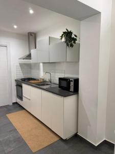 a white kitchen with a sink and a microwave at Casa Carolina Cinisi in Cinisi