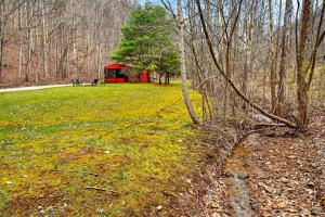 a red cabin in the middle of a field with trees at Creekside Hideaway in Laurelville