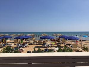 uma praia com guarda-sóis e cadeiras azuis e o oceano em Da Nino e Maria em Marina di Modica