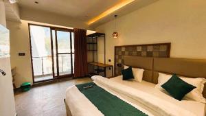 a large bedroom with a large bed with green pillows at Yes Hotel By The Ganges Rishikesh in Rishīkesh