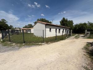 a white building with a fence next to a dirt road at Villa eger in Ruoms