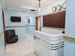 a waiting room with a chair and clocks on the wall at Summer Breeze Guest House in Suru Lere